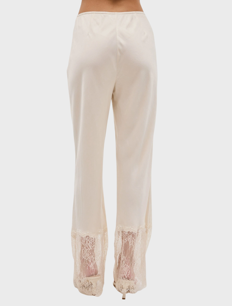 Slim-fit buttercream lace pant with scalloped elastic waistband and sheer lace hem, showcasing refined French seam details.