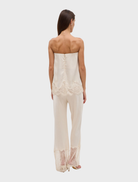 The Visions Lace Pant in buttercream offers a slim silhouette with a scalloped waistband and a light sheer lace hem detail.
