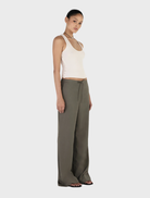 Forest green Caleb pants arranged neatly on a wooden background, emphasizing their modern style and soft material.