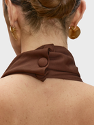 Brown Carrie dress hanging against a neutral background, featuring a timeless style ideal for both day and evening wear.