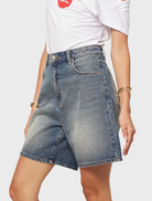 Carrie Short stands elegantly, dressed in a fashionable ensemble, radiating confidence and warmth in her expression.