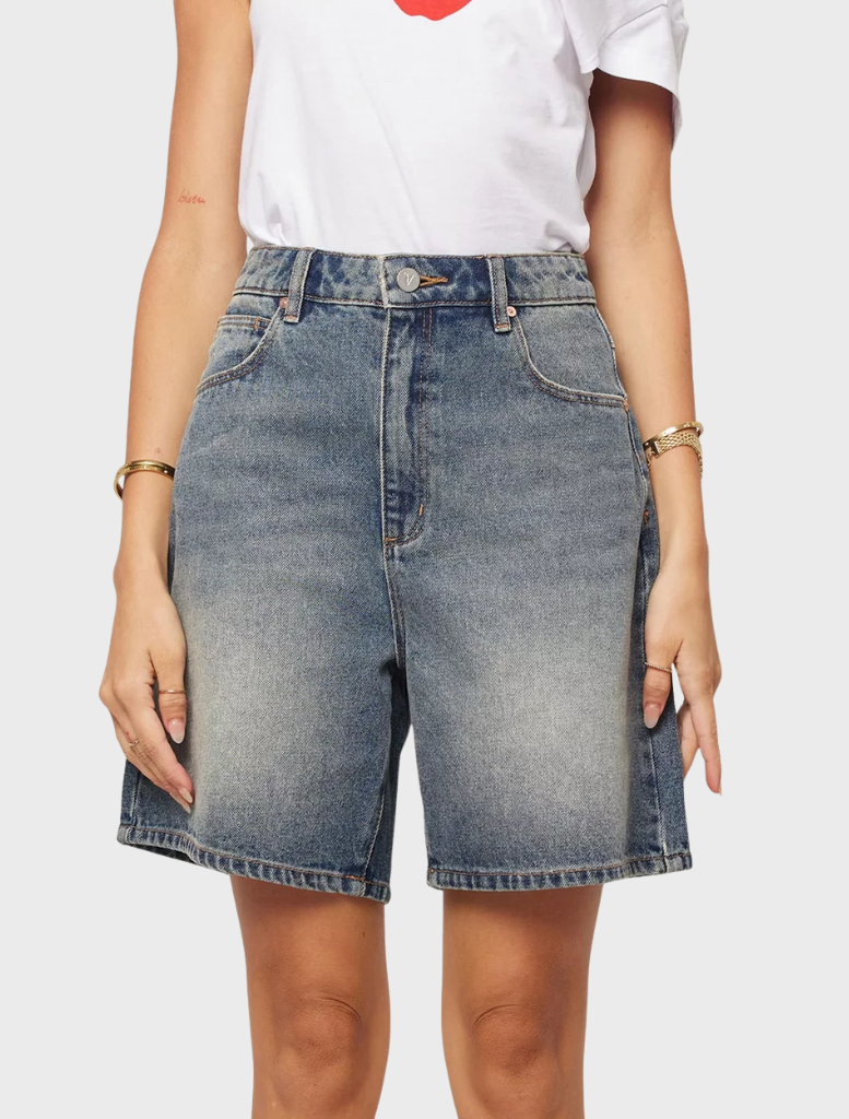 Carrie Short poses with a confident smile, wearing a stylish outfit, showcasing her vibrant personality and charm.