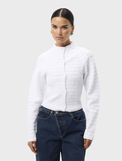 White Carter Cardigan displayed on a hanger, featuring a classic design with long sleeves and a soft texture.