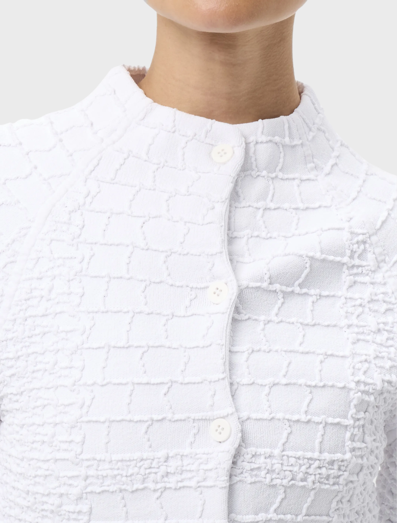 White Carter Cardigan hanging, highlighting its simple design, long sleeves, and soft material for versatile wear.