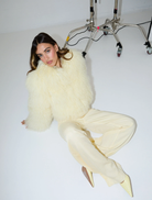 A woman sporting pale yellow pants and a blouse, representing a trendy ensemble.