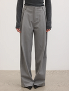 The model displays a chic outfit featuring grey trousers and a black top, ideal for various occasions.