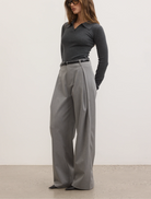 Model wearing grey trousers and a black top, showcasing a stylish outfit suitable for casual or professional settings.
