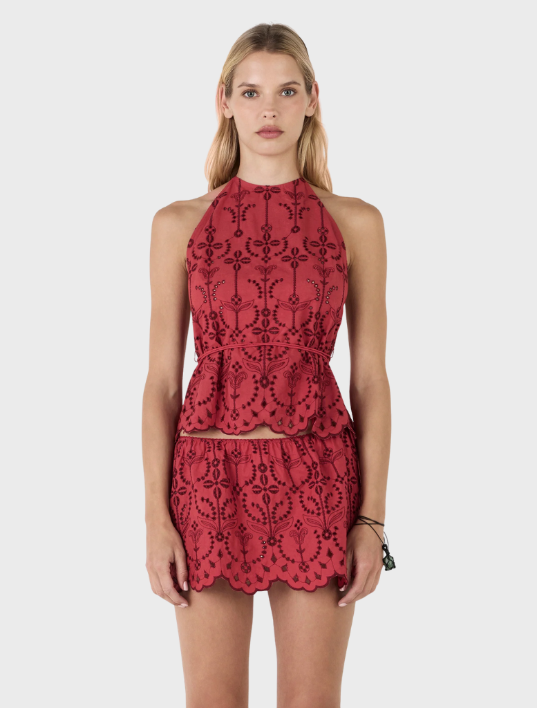 The Darie Mini Skirt in Cherry Anglaise offers a charming lace design and a flared silhouette, suitable for various events.