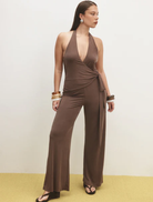 Elegant chocolate Astrid jumpsuit hanging on a rack, showcasing its sleek design and modern silhouette.
