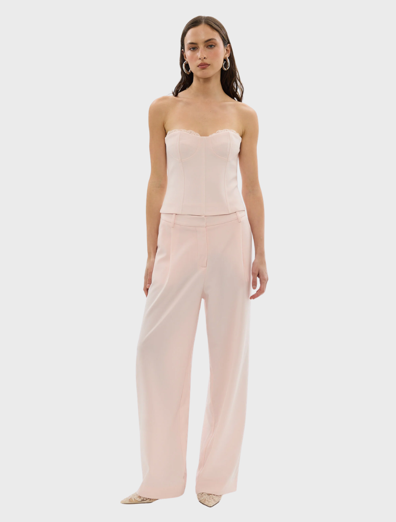 A woman in a pale pink outfit, consisting of a top and pants, highlighting the Cleo Pant style.