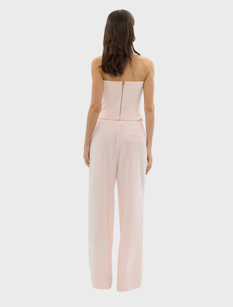 A woman in a coordinated pale pink top and pants, representing the Cleo Pant collection.