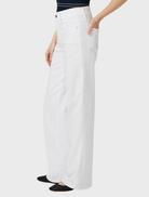 A woman in white wide-leg pants and a striped shirt, featuring the Sasha 32 style in a fresh, crisp look.