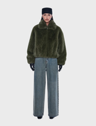 Olive faux fur bomber jacket with oversized fit, standard collar, front zipper, side pockets, and elasticated hem and cuffs.