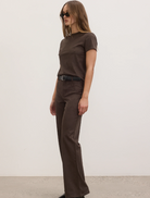  The image features a model dressed in a brown t-shirt and wide-leg pants, presenting a relaxed fashion look.