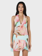 Model in a floral print halter neck dress, named Delilah Scarf Top - Bloom Drift Aqua, showcasing vibrant colors.