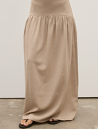 Back view of a woman in a tan dress, showcasing the Delphine Skirt in Nude.