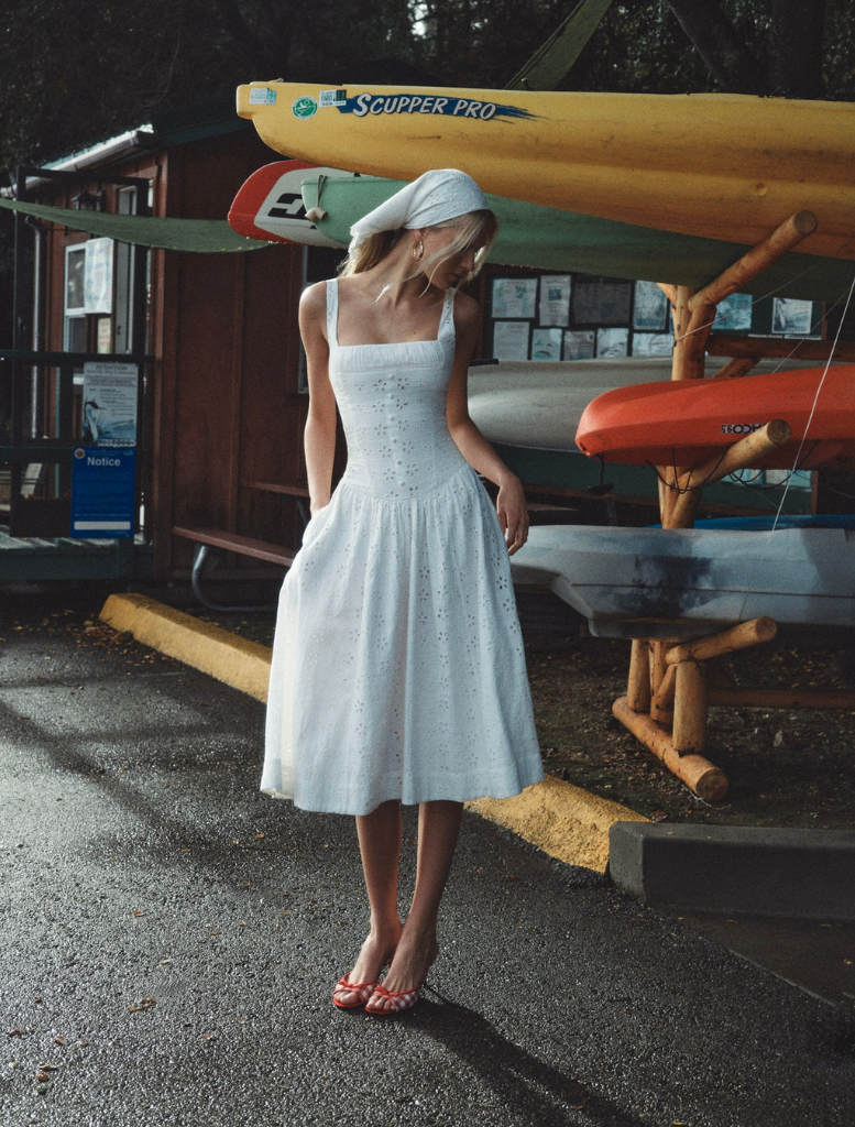White midi dress featuring a whimsical daisy print, designed with a relaxed fit and gentle draping for a romantic style.