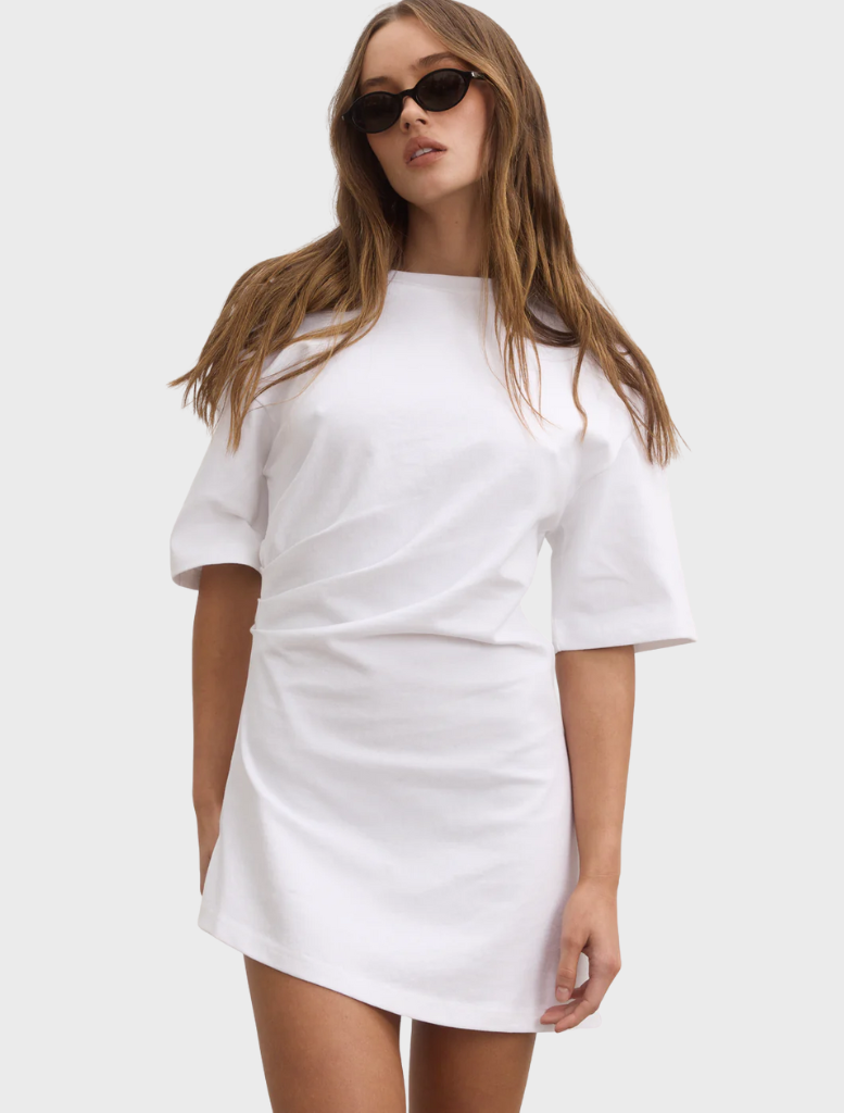 A model is dressed in a white shirt dress, presenting a fresh and modern look suitable for various occasions.
