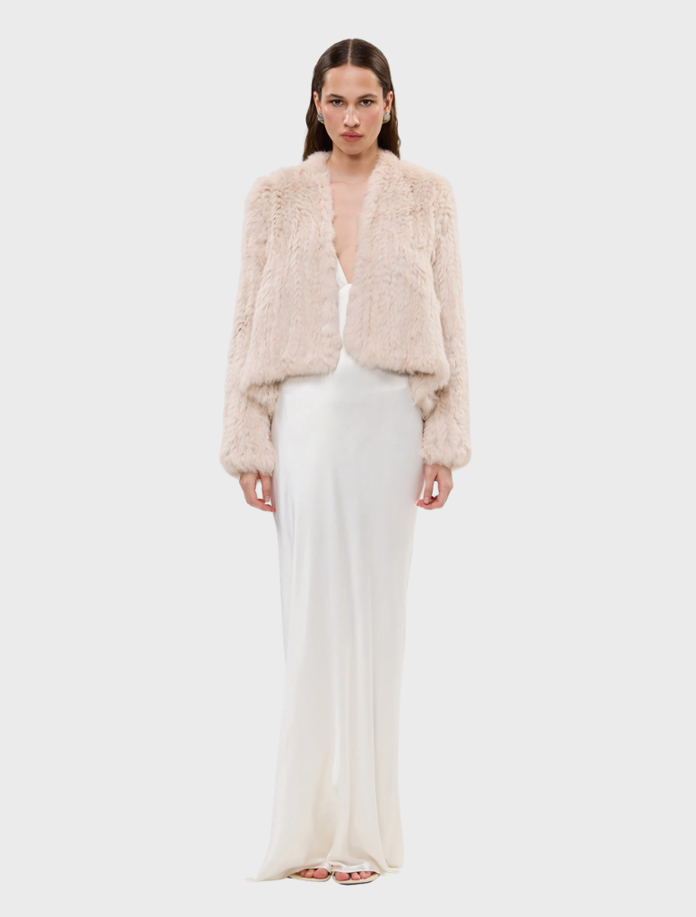 Stone-colored Emma fur jacket displayed on a hanger, showcasing its soft texture and elegant design.