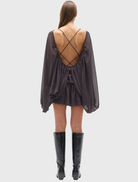 Truffle Evariel Mini Dress showcases a boat neckline, sheer bodice, voluminous sleeves, and a flared skirt with an open back.