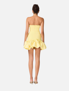 Back view of a woman wearing the Evee Strapless Mini Dress in Lemon, showcasing its vibrant yellow color.