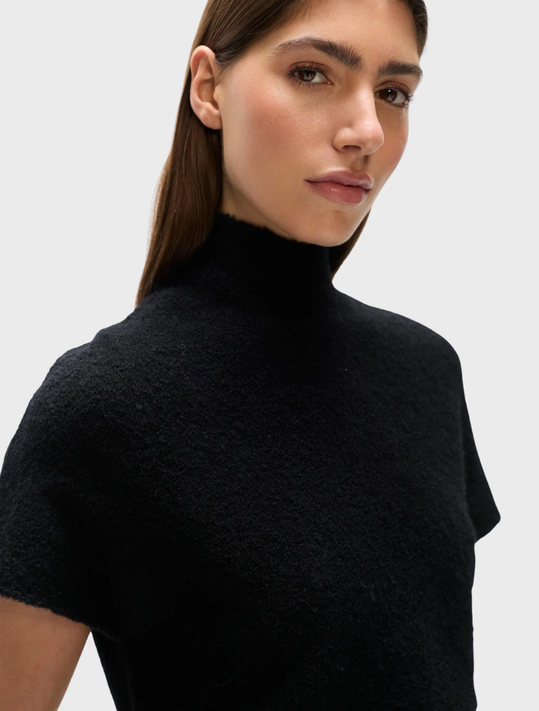 Black Evren knit top laid flat, emphasizing its simple yet chic style and comfortable fit.