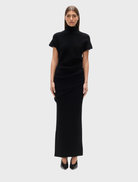 Black Evren knit top displayed on a hanger, showcasing its soft texture and stylish design.