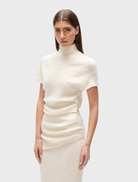 White Evren knit top laid flat, emphasizing its knit pattern and relaxed fit.