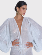 Experimental gown featuring a deep plunging neckline, long sleeves, and a floor-length silhouette in glitter colour.
