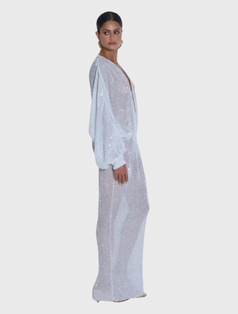 Elegant floor-length gown with a deep neckline, long sleeves, and delicate sparkle fabric, designed for a striking silhouette.