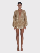 Elegant gold sequin mini dress with a plunging neckline, long sleeves, and a flowing design, perfect for special occasions.
