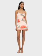 Fitted mini dress in peach with a floral pattern, showcasing a stylish and feminine design.