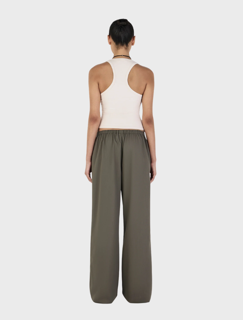 A pair of Caleb pants in forest green, laid flat on a rustic wooden table, highlighting their stylish cut and texture.