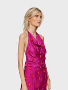 A woman in a vibrant fuchsia dress carries an orange bag, creating a striking and fashionable appearance.