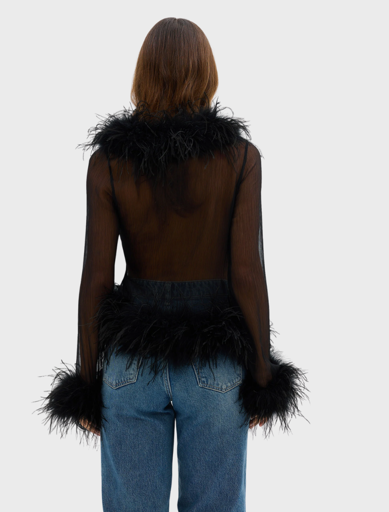 A model in a black Gigi Feather Blouse, featuring feather accents, exemplifying modern fashion and elegance.