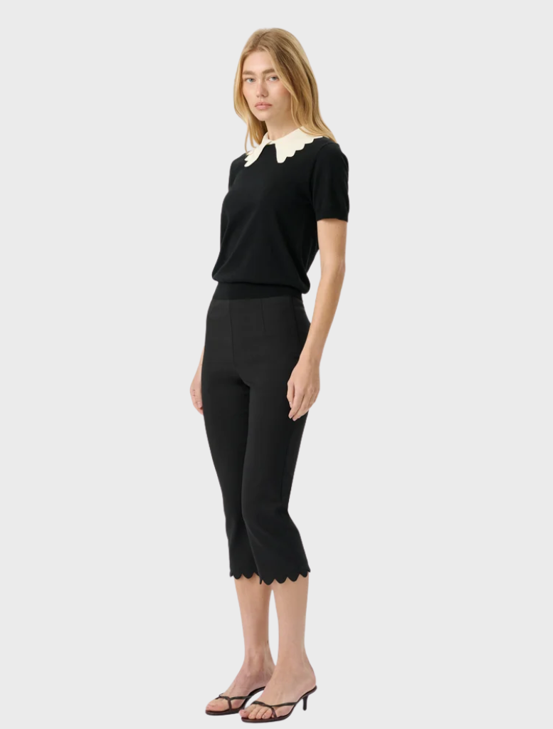 Elegant black knit top with a sleek silhouette, short sleeves, and a contrasting scalloped collar for a vintage touch.