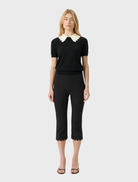 Black fitted knit top with short sleeves and a scalloped collar, offering a modern and vintage-inspired design.