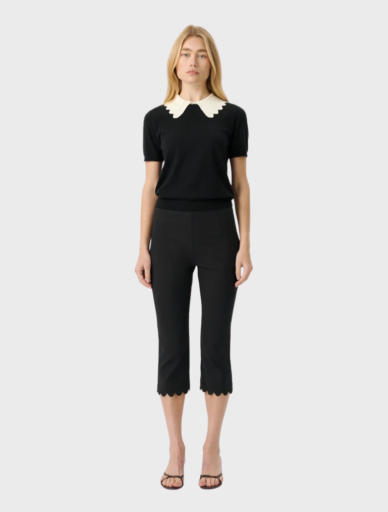 Black fitted knit top with short sleeves and a scalloped collar, offering a modern and vintage-inspired design.