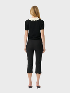 Sophisticated black knit top featuring a body-hugging fit, short sleeves, and a playful scalloped collar detail.