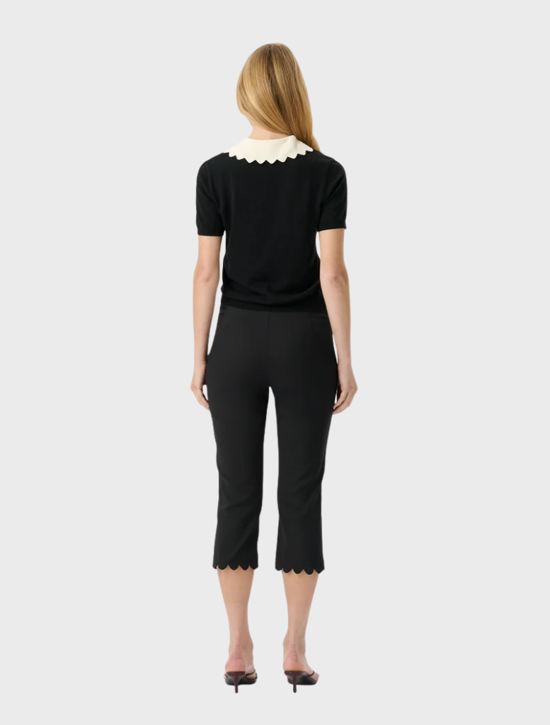Sophisticated black knit top featuring a body-hugging fit, short sleeves, and a playful scalloped collar detail.