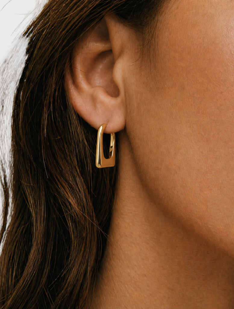 A pair of gold Amelia hoops earrings, featuring a sleek and modern design, presented against a neutral backdrop.