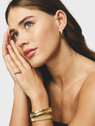 Sabrina's gold cuff bracelet, characterized by its contemporary style and polished surface.