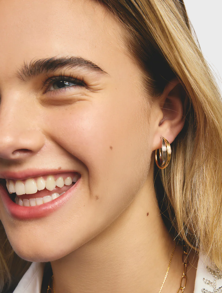 A pair of gold and silver hoop earrings, highlighting their circular shape and reflective surfaces against a neutral backdrop.