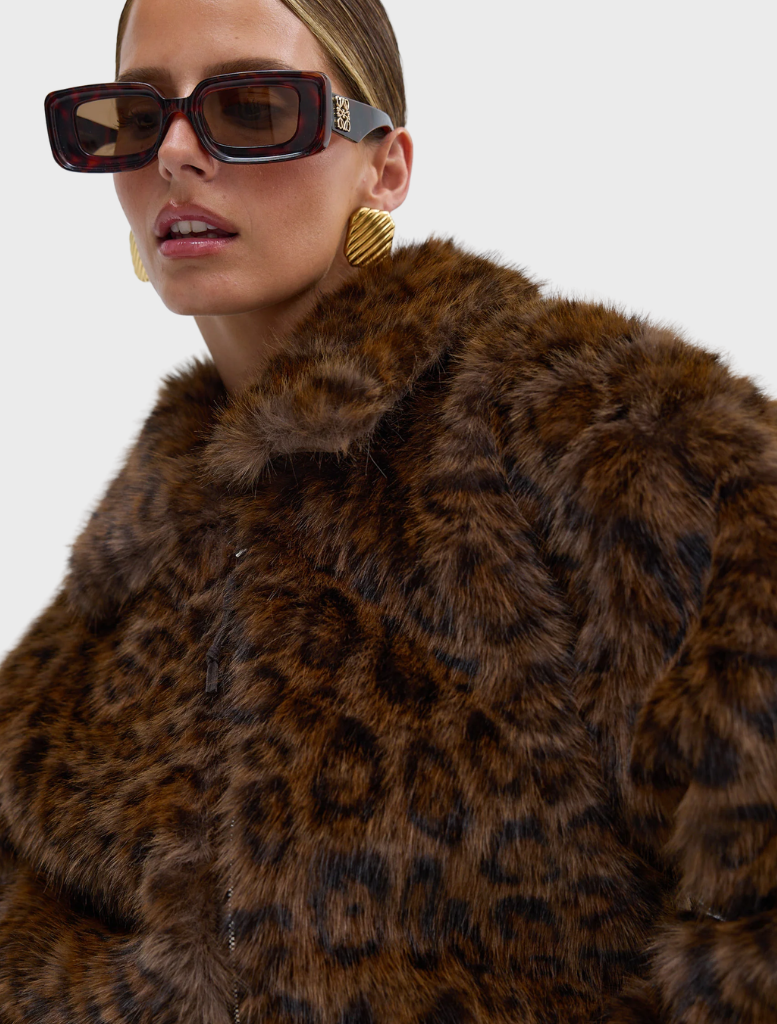 Chocolate leopard faux fur bomber jacket displayed on a hanger, showcasing its stylish design and texture.