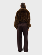 Chocolate leopard faux fur bomber jacket displayed on a hanger, showcasing its stylish design and texture.