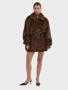 A chocolate leopard faux fur bomber jacket, featuring a trendy design, hanging against a neutral background.