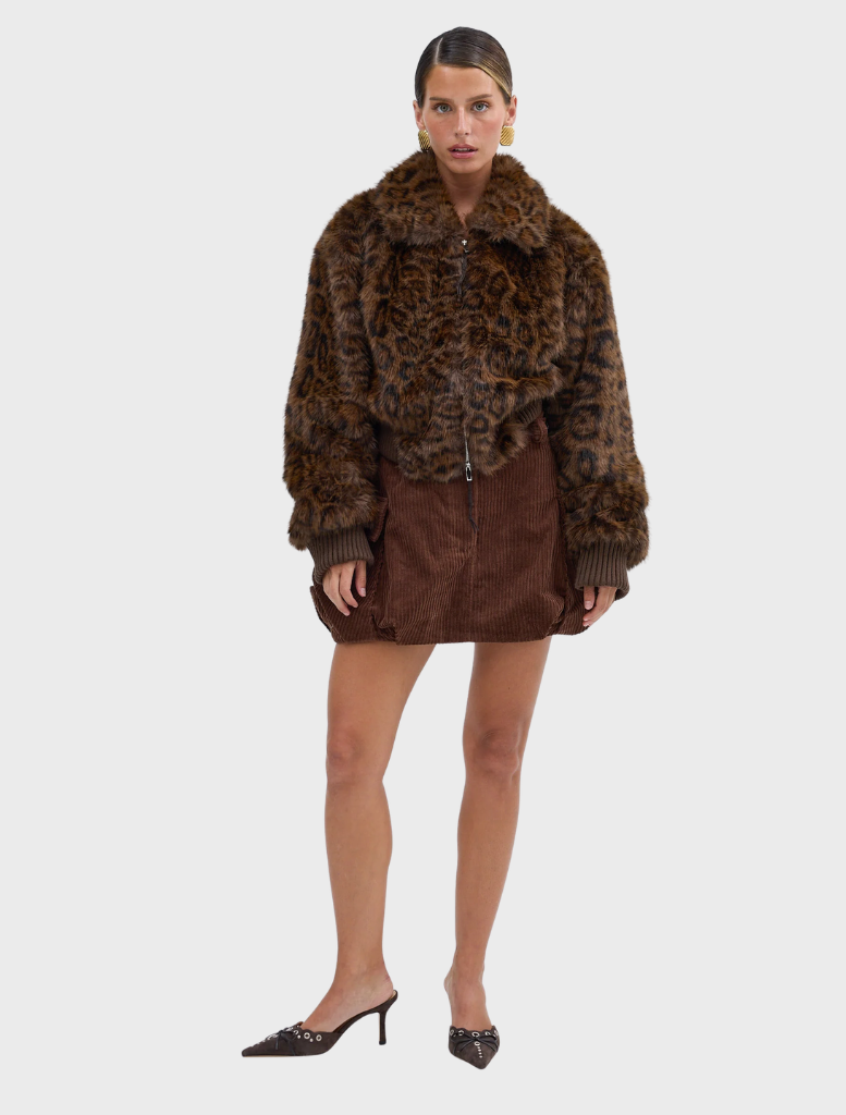 A chocolate leopard faux fur bomber jacket, featuring a trendy design, hanging against a neutral background.