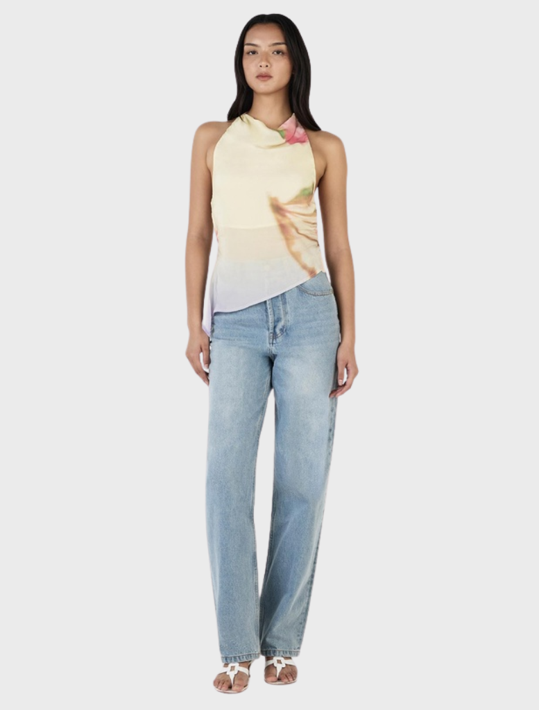 A model presents the Iris Halter Top in Golden Drift, highlighting its yellow fabric and attractive floral print design.