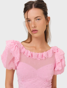 A pink mini dress with eyelet patterns, showcasing a feminine silhouette and delicate lace accents.
