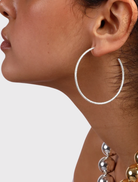 The Extra Her Hoops in silver have a hammered texture, stud back closure, and are crafted for comfort and style.